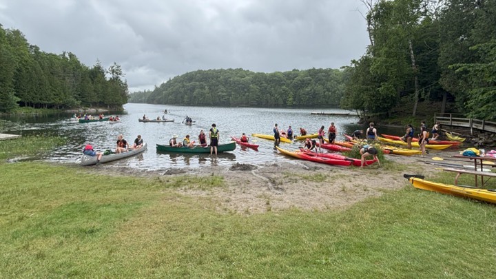 A group of students preparing canoes next to water